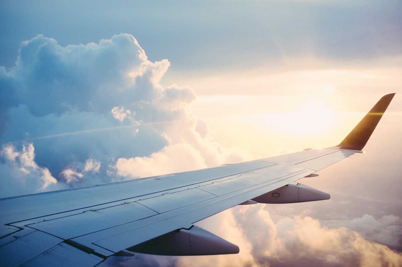 Asa de avião comercial acima das nuvens ao pôr do sol