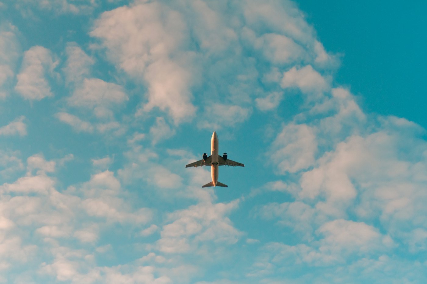 Avião comercial visto de baixo, entre nuvens