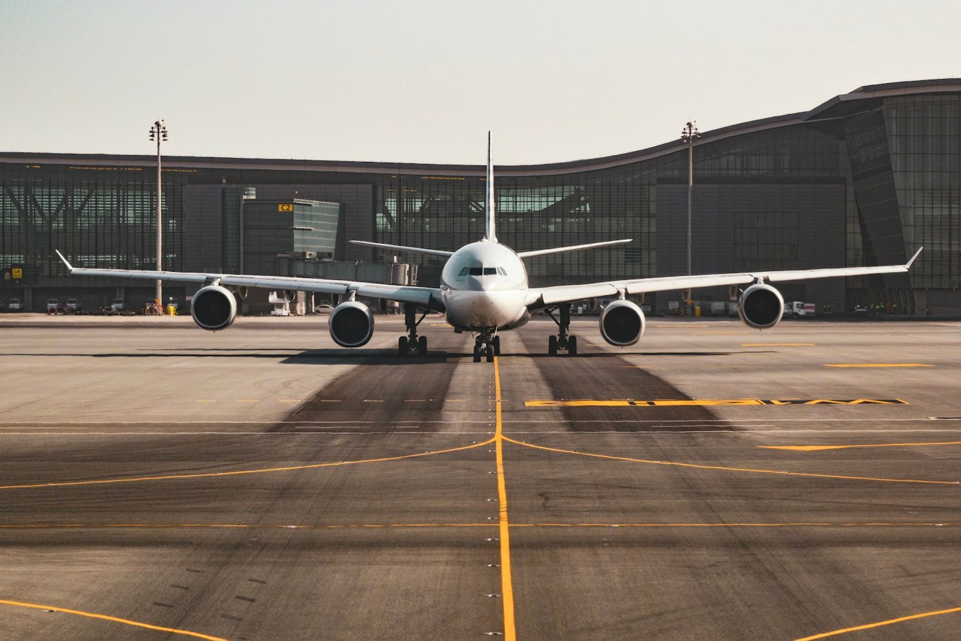 Avião de frente no pátio, com o terminal do aeroporto ao fundo