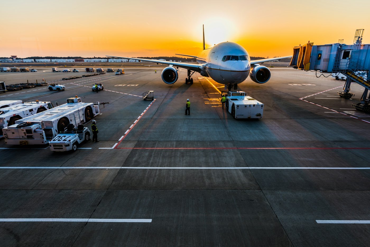 Avião no pátio do aeroporto ao entardecer, ao lado da ponte de embarque